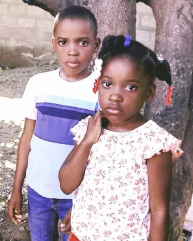 Decelyn and Rose-Esther pose for a photo in front of a tree.