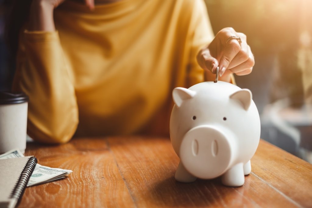 woman hand putting coin into piggy bank